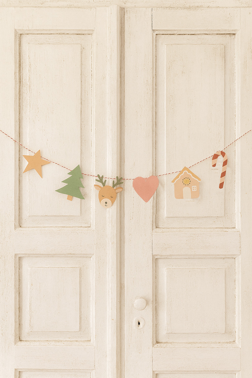 Weihnachtliche Papier-Girlande in sanften Naturtönen an einer hellen Tür – die DIY-Weihnachtsdeko gibt es als gratis Download für Weihnachten auf titatoni.de